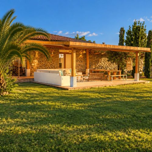 Porche cubierto de la casa entre palmeras y césped – casa rural Aprisco de Candeleda (Ávila)